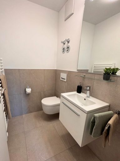 Gäste-WC renoviert mit hellbraunen Fliesen, Handtuchheizkörper und modernem Waschbecken