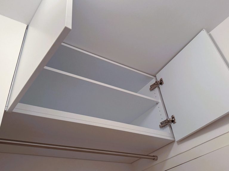 Weißer Deckenschrank mit zwei offenen Türen und zwei Regalen.