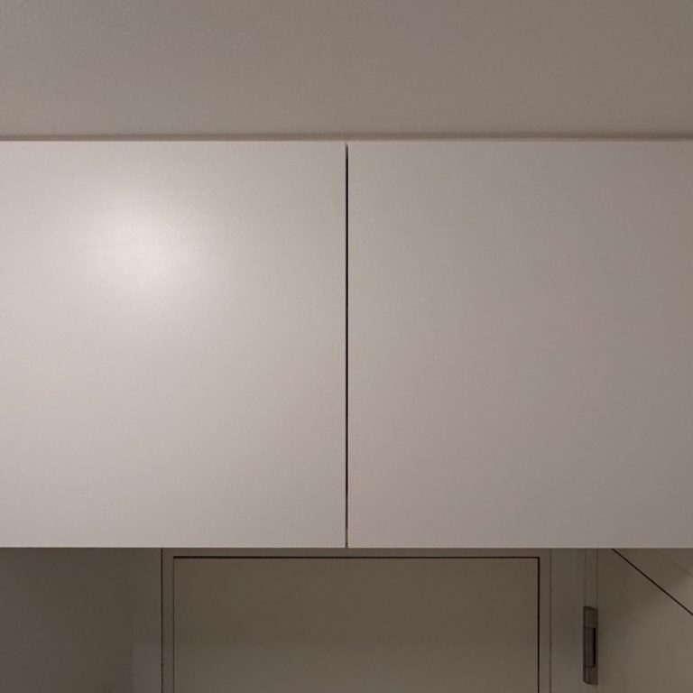 Zwei helle, geschlossene Oberschränke an einer Wand im Flur, direkt unter der Decke